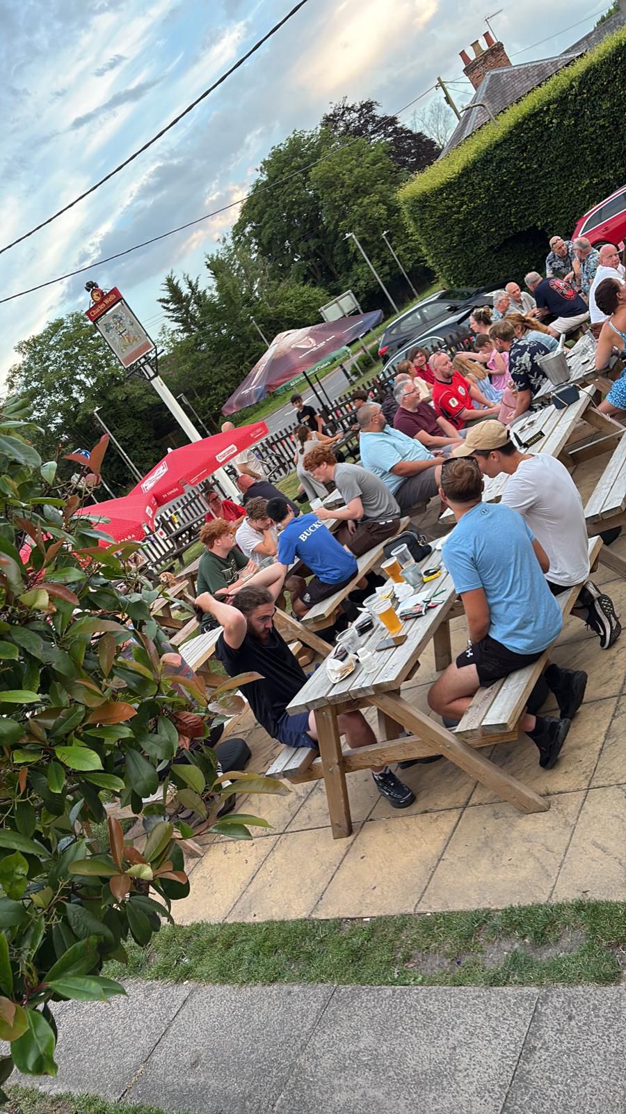 A busy afternoon in the beer garden at The Chandos Arms, with groups enjoying drinks at tables on the lawn.